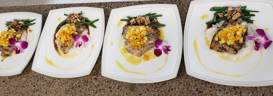 Plated entrées with orchids lined up for service