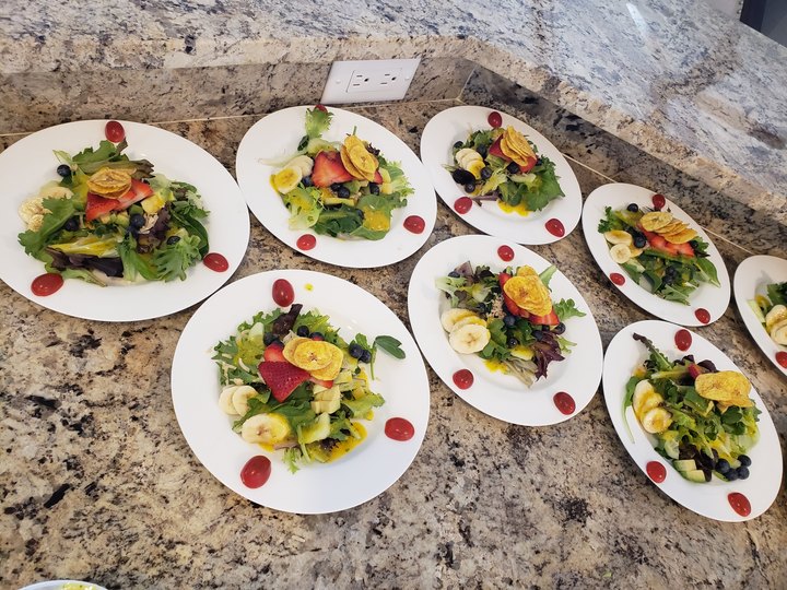 Plated salads with fruit, lined up for service